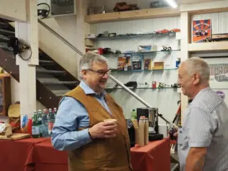 Zwei Gäste im Gespräch an der Bar vor einer Wand mit Oldtimer-Modellen