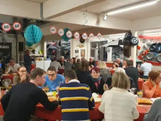 Volle Halle mit Gästen an langen Tischen