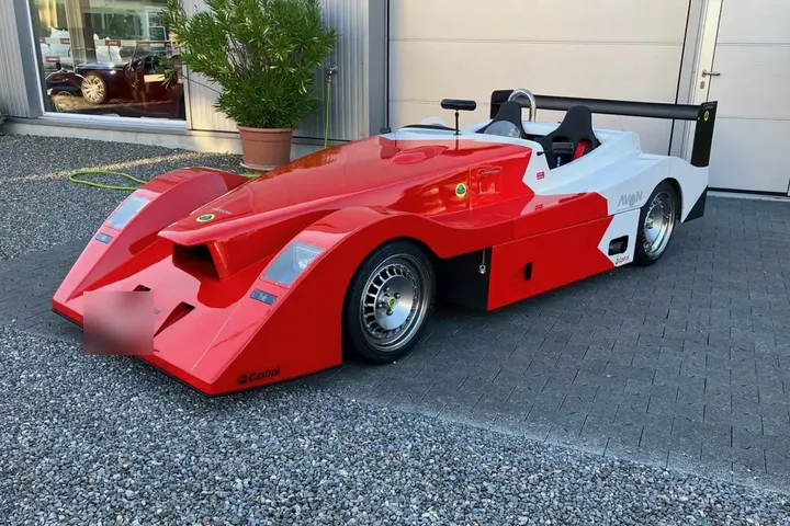 Rot-weisser Lotus-Rennsportwagen vor der Halle